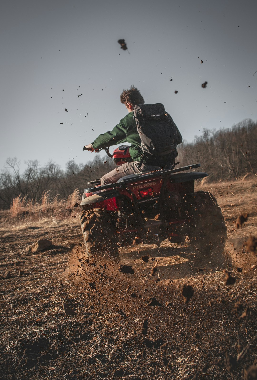 Man Riding Red Atv On Brown Field During Daytime man riding red atv on brown field during daytime