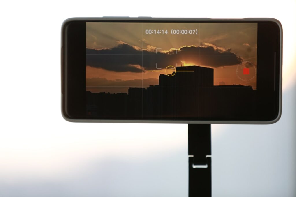 Smartphone screen displaying a sunset over buildings.