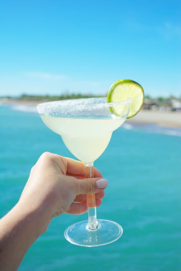 a hand holding a martini glass with a lime slice on the rim