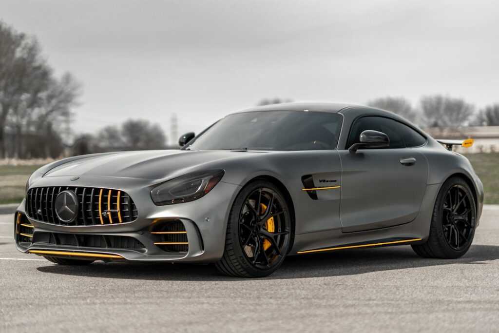 A matte grey sports car with yellow accents parked on an asphalt surface
