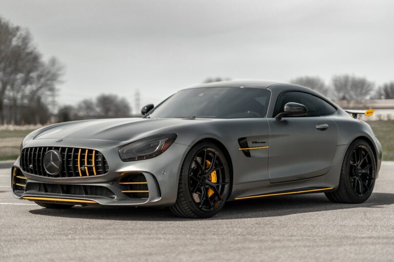 A matte grey sports car with yellow accents parked on an asphalt surface