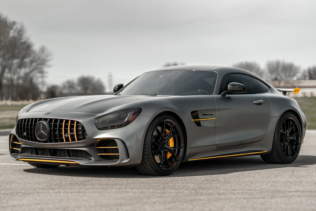 A matte grey sports car with yellow accents parked on an asphalt surface