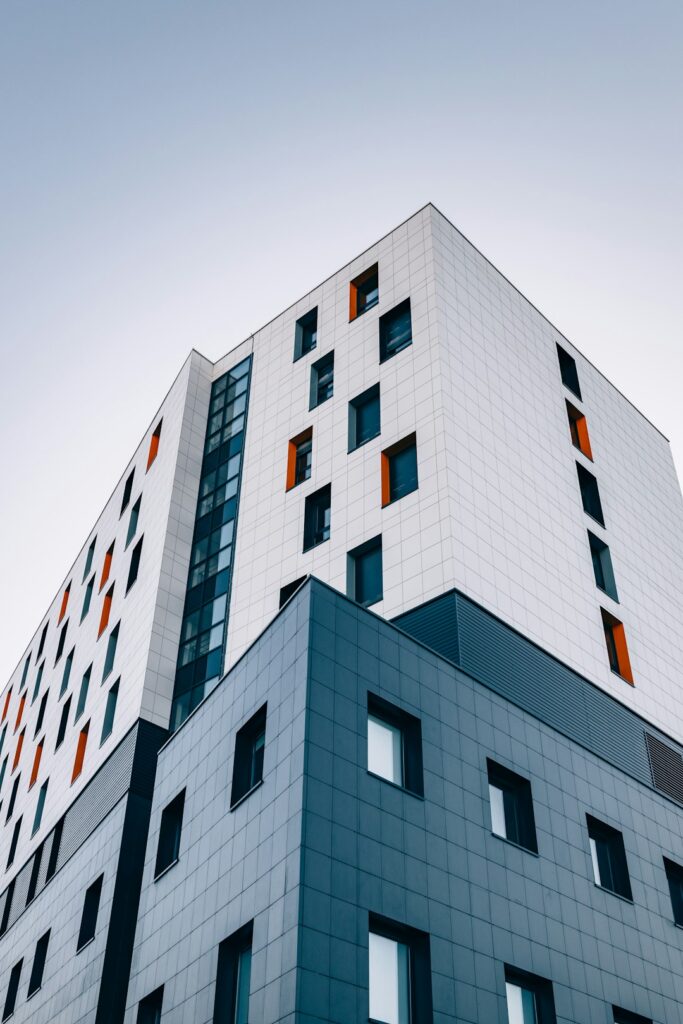 A modern building with white and grey tiled facades and orange window accents